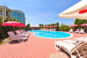 a pool with chairs and umbrellas next to a building at Hotel Dragović Smederevo in Smederevo
