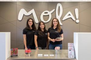 tres mujeres de pie delante de un signo mca en Mola Suites en Madrid