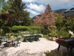 a patio with a table and chairs and trees at 965 avenue leopold Fabre GITE LE LANTIER in Lans-en-Vercors