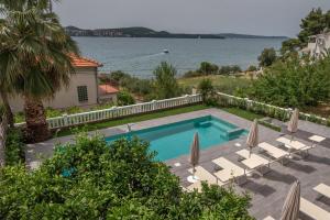 una piscina con sedie a sdraio e ombrelloni di Villa Ana Trogir a Trogir