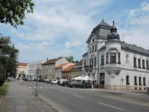 biały budynek z wieżyczką na ulicy miejskiej w obiekcie Olymp penzion w mieście Komárno