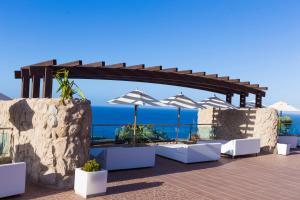 a patio with white tables and umbrellas and the ocean at Gloria Palace Royal Hotel & Spa in Puerto Rico de Gran Canaria