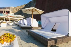 a row of chairs and an umbrella on a patio at Gloria Palace Royal Hotel & Spa in Puerto Rico de Gran Canaria