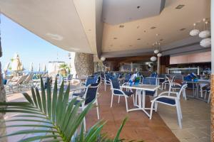 a restaurant with white tables and chairs and a beach at Gloria Palace Royal Hotel & Spa in Puerto Rico de Gran Canaria