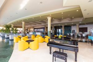 a lobby with a piano and yellow chairs at Gloria Palace Royal Hotel & Spa in Puerto Rico de Gran Canaria