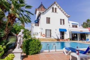 a villa with a swimming pool in front of a house at Hotel Capri in Sitges