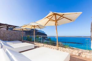 a patio with two white chairs and an umbrella at Gloria Palace Royal Hotel & Spa in Puerto Rico de Gran Canaria