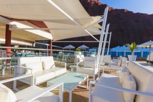 a patio with white chairs and tables and a mountain at Gloria Palace Royal Hotel & Spa in Puerto Rico de Gran Canaria