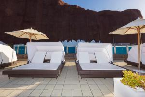 two lounge chairs and umbrellas on a patio at Gloria Palace Royal Hotel & Spa in Puerto Rico de Gran Canaria