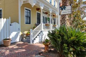 une maison jaune avec une terrasse couverte blanche et des escaliers dans l'établissement Green Palm Inn, à Savannah