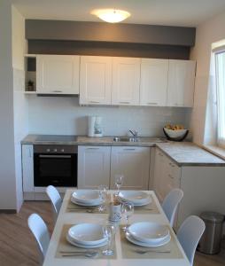 a kitchen with a table with plates and wine glasses at Apartmani Marin in Vrbnik