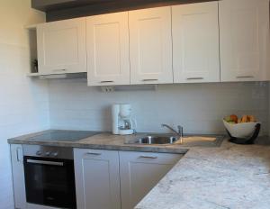 a kitchen with white cabinets and a sink at Apartmani Marin in Vrbnik