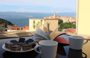 a plate ofbrownies and coffee cups on a table with a view at Apartmani Marin in Vrbnik