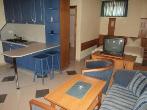 a living room with a couch and a kitchen with a tv at Bakony Panzió in Tótvázsony