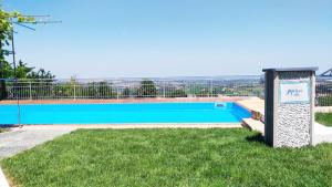 een blauw zwembad met een bord in het gras bij Mulino del Mare in Saludecio