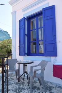 een patio met een tafel en stoelen en een raam bij Occasus Room in Halki