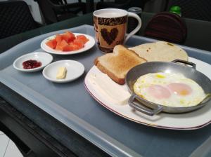bandeja de desayuno con huevos, tostadas y una taza de café en Hotel Meson de las Flores, en Armenia