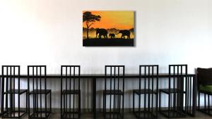 a table with chairs and a painting of elephants at Hiranya Mountain View Hostel Kandy in Kandy