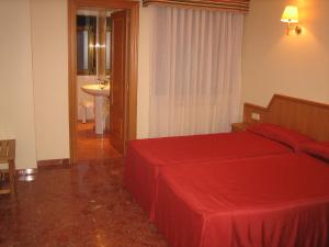 a bedroom with a red bed and a sink at Hotel Chané in Puebla de Alfindén