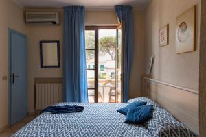 a bedroom with a bed with blue pillows on it at Hotel Corallo in Pomonte