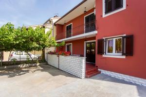 a red house with a balcony and a car at Elena Apartment- Spacious for 6, 2 Bathrooms, Free Parking in Rovinj