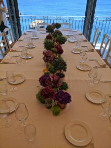 a long table with wine glasses and flowers on it at Hotel Mezzatorre in Ventotene