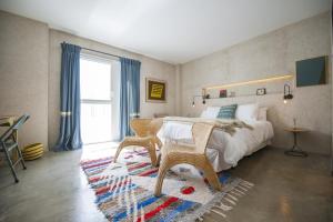 a bedroom with a bed and a chair and a window at Kook Hotel Tarifa in Tarifa