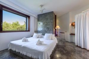 a bedroom with a bed with white sheets and a window at Villa Can Azul in Cala Tarida