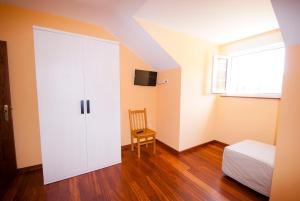 1 dormitorio con armario blanco, cama y ventana en As Viñas, en Viveiro