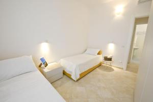 a white bedroom with two beds and a bathroom at Blue Sea Villas by Wonderful Italy in Ostuni +24 photos