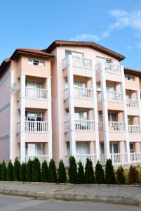a pink building with white balconies and trees at studio ASI in Obzor