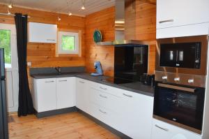 a kitchen with white cabinets and black appliances at Chalet Les Prés in Neubois +13 photos