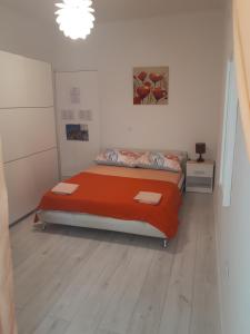 a bedroom with a bed with orange sheets on it at Apartmani Ivana in Lopar