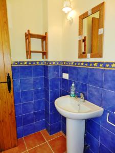 a blue tiled bathroom with a sink and a mirror at La Quinta de María Luisa in Zahora