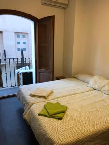 ein Schlafzimmer mit einem Bett mit zwei grünen Handtüchern darauf in der Unterkunft Casa Rural Xàtiva in Xàtiva