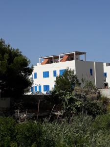 a white building with blue windows on the side of it at Casa Nettuno Favignana in Favignana