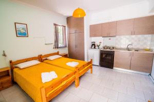a bedroom with a yellow bed and a kitchen at Elena Apartments in Kanali