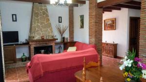 a living room with a red couch and a fireplace at Casa Encina - Encinasola Turismo Rural. in Alora