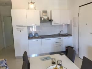 uma cozinha com armários brancos e uma mesa em Residenza la Gioiosa. em Scarlino