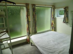 a bedroom with a bed and a large window at chalet de la vallée des prés in Oignies-en-Thierache