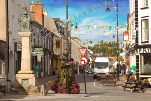 eine belebte Stadtstraße mit einem Uhrturm und Blumen in der Unterkunft Luxury Town House-Apartment Carrick-on-shannon in Carrick on Shannon