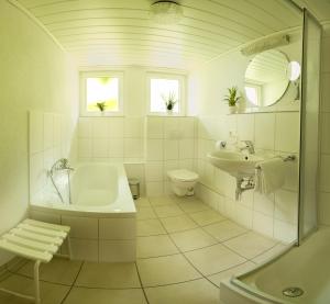 Baño blanco con bañera y lavamanos en Ferienwohnung am Schneeberg en Titisee-Neustadt