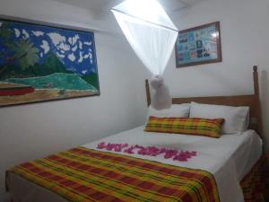 1 dormitorio con 1 cama y una pintura en la pared en cocoa pod studio, en Soufrière