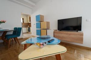 uma sala de estar com uma mesa e uma televisão em Central Park Lux em Arandjelovac