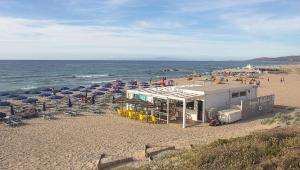 a beach with chairs and umbrellas and the ocean at CASA VACANZA VALLEDORIA 2 in Valledoria