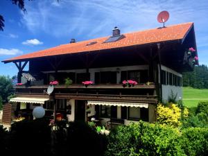 a house with a red roof with flowers on the balcony at Gästehaus Grieser in Hopferau