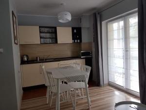 a kitchen with a table and chairs and a kitchen with a window at Apartament Grześ in Szklarska Poręba