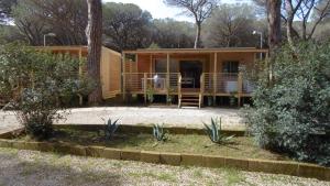 a cabin in the woods with a porch at Camping Eden in Marina di Grosseto