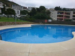 a large blue swimming pool with buildings in the background at Apartamento Almadraba in Roses
