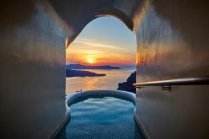 a view of a sunset through an arch in a building at Celestia Grand in Fira